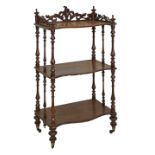Victorian walnut serpentine front three tier what-not having a carved gallery top and standing on