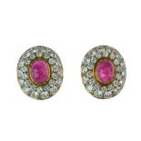 Pair of ruby and diamond earclips, the oval cabochon 9.5mm x 7.5mm, enclosed by twenty-eight