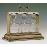 Silver plated tantalus containing three cut glass decanters, cast carrying handle to the top and