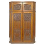 Early 20th Century Arts & Crafts oak corner hall wardrobe having two upper doors with heavily carved