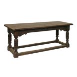 Antique oak refectory dining table having a carved frieze and standing on turned and acanthus carved