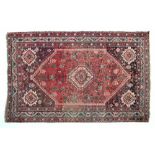 Caucasian wool rug decorated with a large central medallion on a red and blue ground within multi