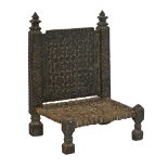 Asian heavily carved low chair, Pakistan or Northern India, having a rush seat and standing on
