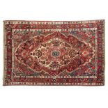 Middle Eastern wool rug decorated with a central medallion on a red and blue ground within multi