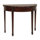 George III crossbanded mahogany demi lune fold over card table, the frieze with carved decoration