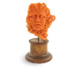 An Italian red coral sculpture Engraved and modelled as the head of the Medusa, on wooden base