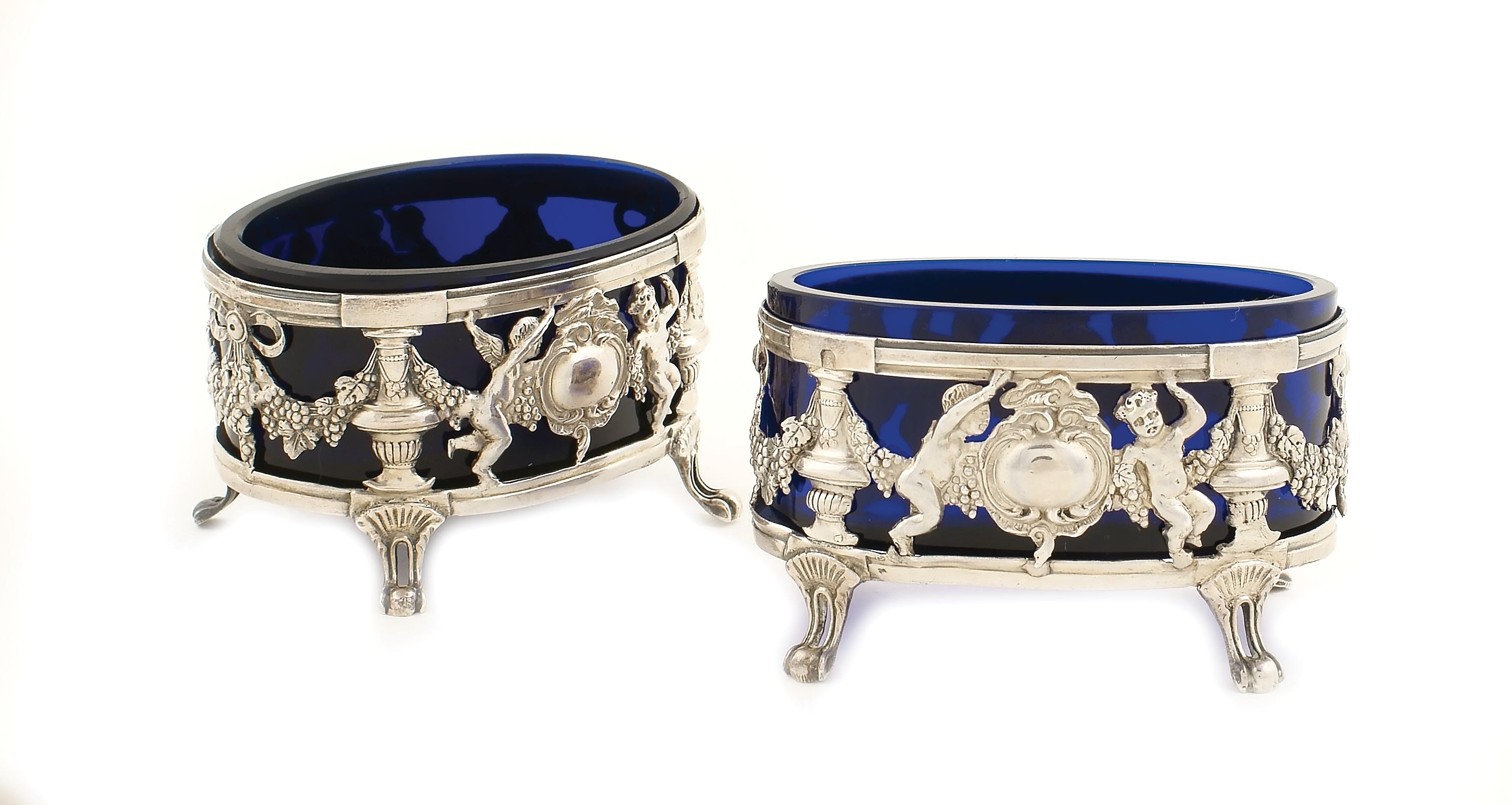 A pair of French silver saltcellars With repoussé and chasing decorations, glass interior and