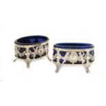 A pair of French silver saltcellars With repoussé and chasing decorations, glass interior and