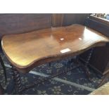 A 19th century walnut side table with shaped top resting on cross stretcher barley twist supports.