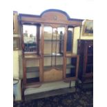 An Edwardian mahogany mirror back display cabinet with central glazed door and painted urn and