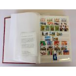 A red Royal Mail stock book containing a selection of mint unused GB stamps.