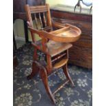 A late 19th century wooden child's articulated highchair with cut-out seat and ratchet mechanism