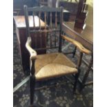 A 19th century oak framed country armchair with straw seat and turned cross stretcher supports.