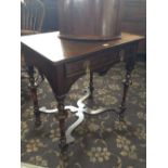 An oak side table with single drawer, resting on shaped and turned supports.