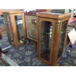 A pair of late 19th century French Empire style walnut glazed side cabinets with brass mounts.