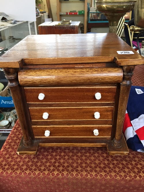A miniature mahogany chest of three drawers with pillar supports and secret drawer.