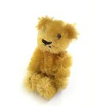 Miniature Schuco Teddy Bear: golden mohair, boot button eyes, stitched nose and mouth, metal frame.