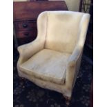 A late 19th century wingback armchair resting on gilded front supports.