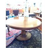 A tilt-top Victorian mahogany dining table resting on drum support.