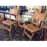 A pair of oak framed arts and crafts chairs with leather backs and seats.