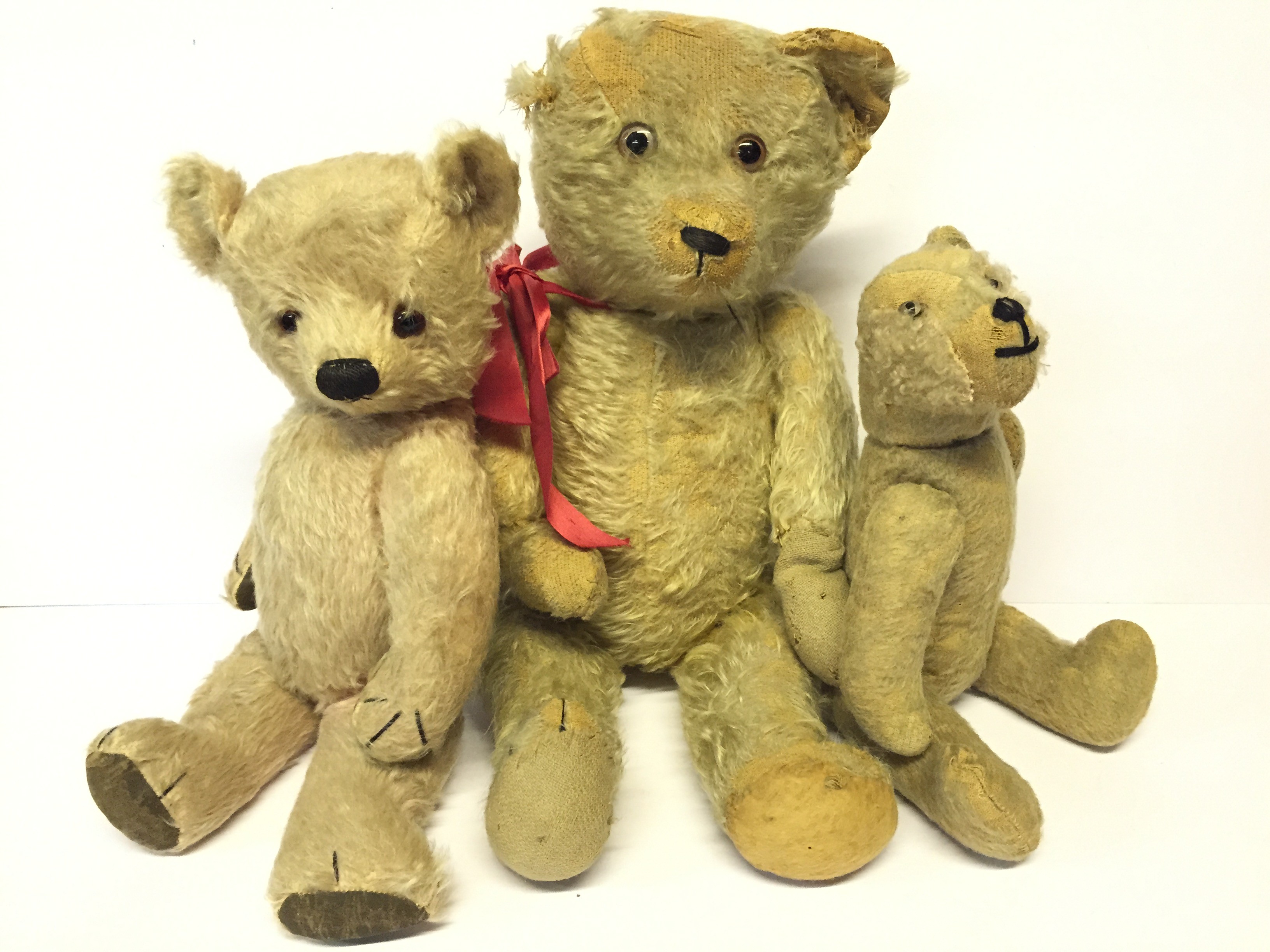 Three Teddy Bears, the largest straw-filled with small hump to back, elongated snout,