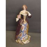 A C19th Continental porcelain figure of a lady wearing a long dress painted with flowers, standing