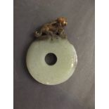 A Chinese pi-disc shaped jade pendant with a carved kylin surmount, 2¾'' long