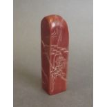 A Chinese chicken blood soapstone seal blank with carved landscape and figures,