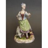 A German ceramic figure of a shepherdess with two sheep and a dog, on a gilt scrolled base, marked,