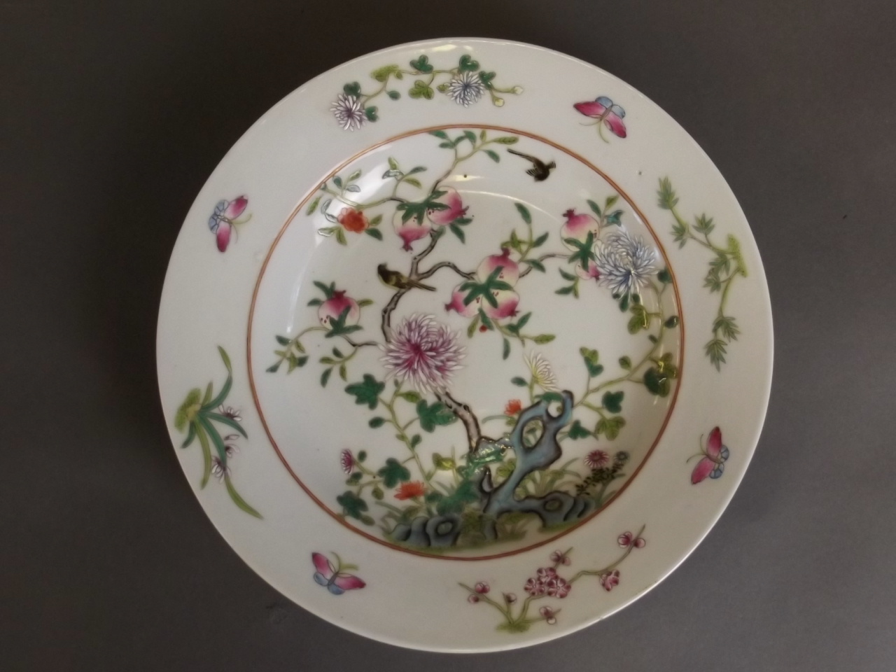 A Chinese porcelain dish with painted enamel decoration of a pomegranate tree,