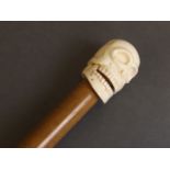 A bone handled walking stick in the form of a skull,