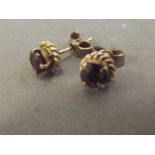 A pair of unmarked gold ear studs set with garnets
