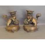 A pair of Chinese bronze kylin resting on pierced balls, on circular bases, 10'' high
