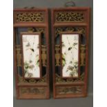 A pair of Chinese ceramic plaques decorated with birds perched on bamboo, within a pierced and