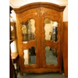 An C18th French cherry and fruitwood armoire with carved decoration of scrolling foliate designs and