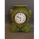 A green ground ceramic cased mantle clock with classical decoration, 11'' high