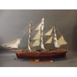 A wood model of a C19th three-masted sailing ship with twelve guns, mounted on a wooden stand with