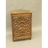 A standing oak corner cabinet with a decoratively carved door opening to reveal a loud speaker, 20''