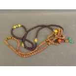 A string of coloured beads and pierced white metal, and a nut beaded necklace, 25'' long
