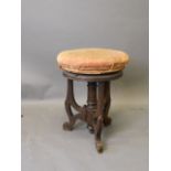 A Victorian walnut revolving piano stool on pierced supports with scrolled ends, 19½'' high