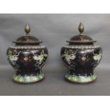 A pair of Oriental black ground cloisonné jars and covers, decorated with dragons chasing the