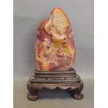 A Chinese soapstone ornament carved with a seated man burning incense, on a wood stand, 9'' high