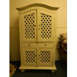 A painted cabinet with arched top, latticed doors and two drawers, standing on bun supports, 40''