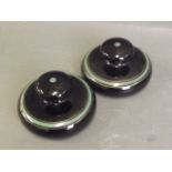 A pair of pottery paperweights with a high gloss black glaze and green line decoration, 4'' diameter