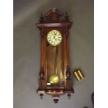 A C19th Vienna wall clock, the walnut case with turned and moulded decoration, the enamel dial
