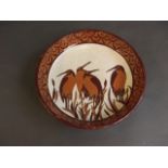 A ceramic Longwy style bowl decorated with wading birds, 10½'' diameter