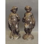 A pair of white metal figures of a boy and girl in traditional clothing, 5½'' high