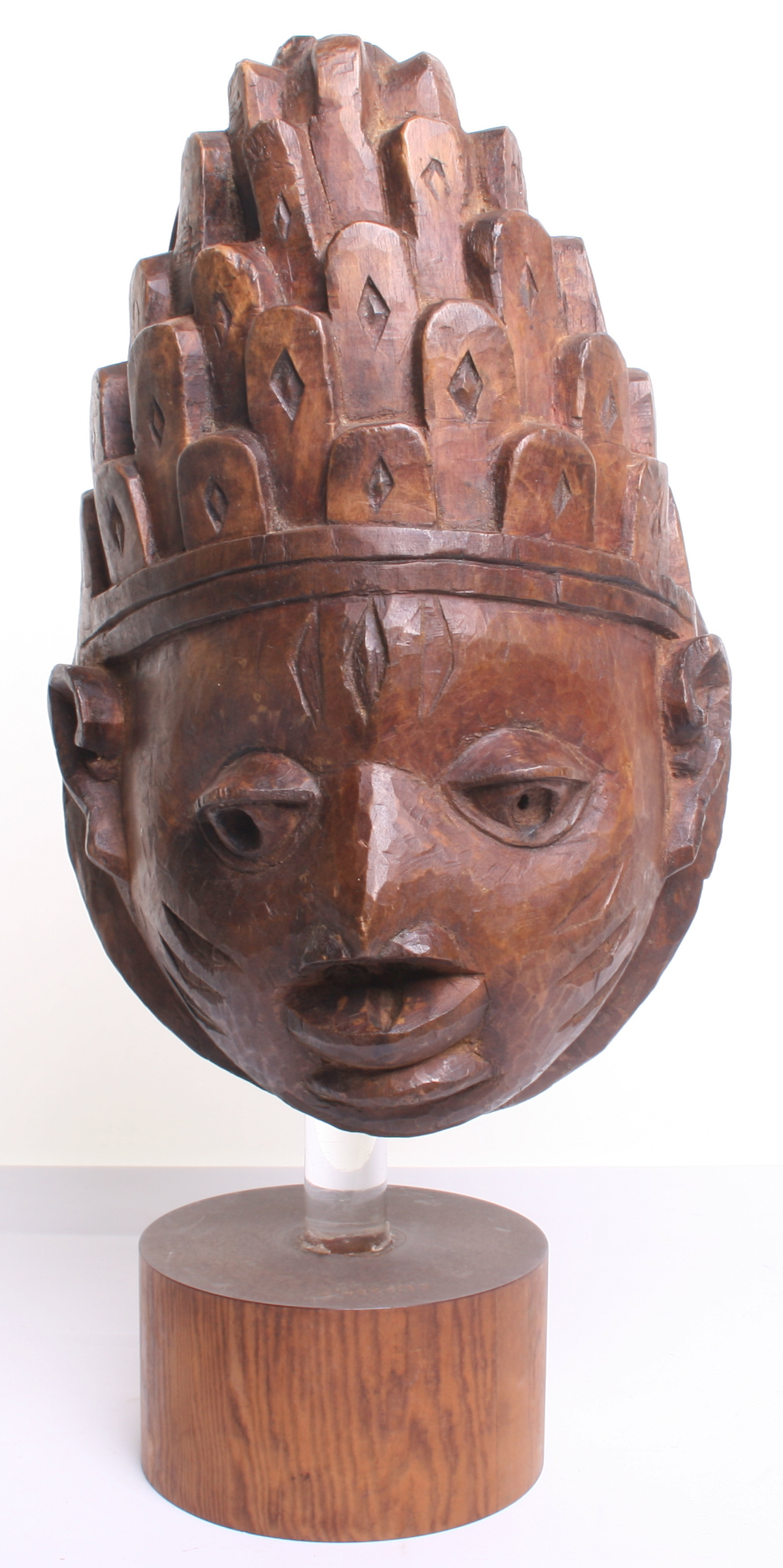 African Wooden Mask carved as a stylised human face, stained for effect, with tall crown of