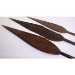 Three Assorted West African Carved Wooden Paddles, maximum 66.5"overall, the swollen leaf-shaped