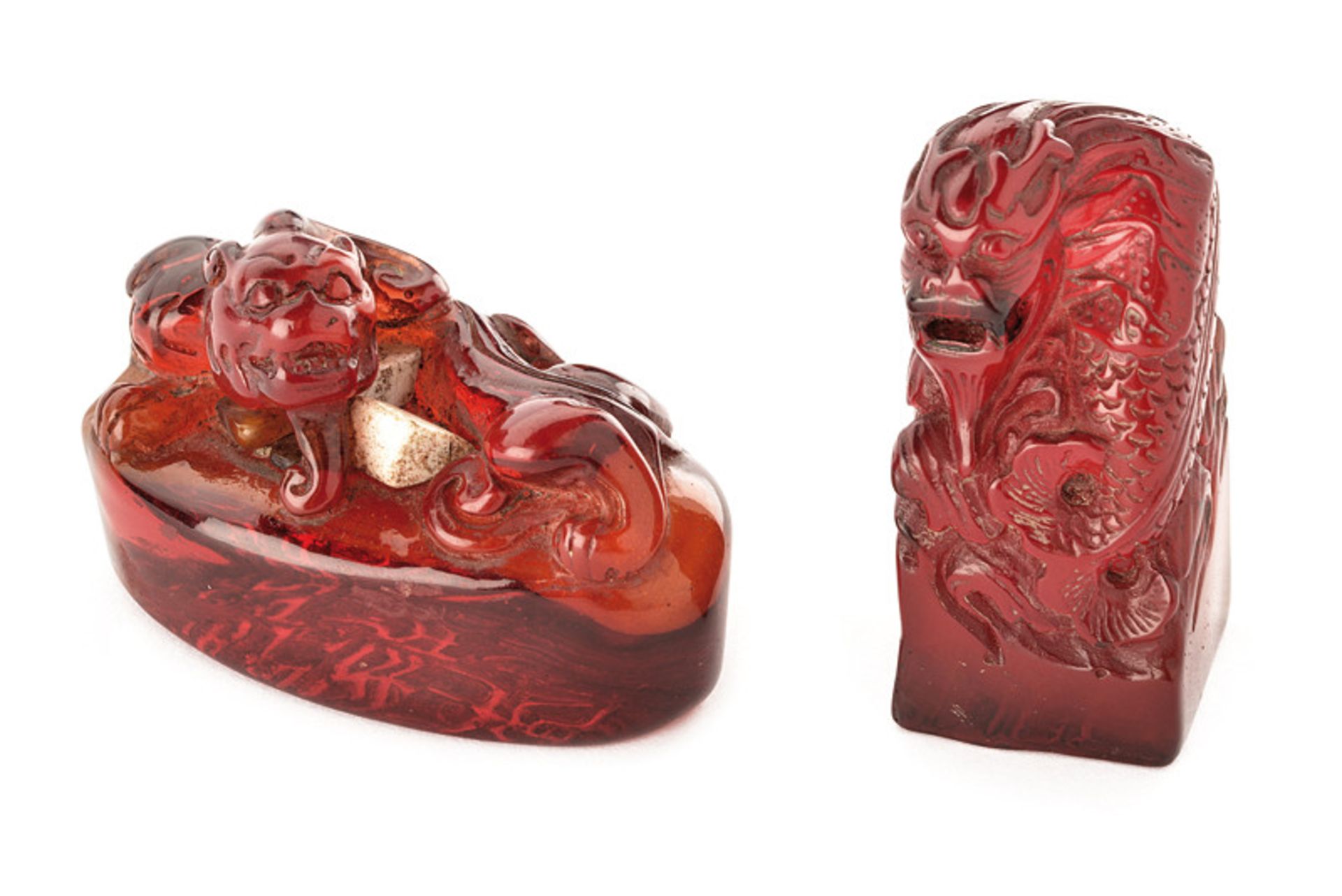 A lot of two signets dating: 19th Century provenance: China Of red amber. Chiselled as dragon or Foo